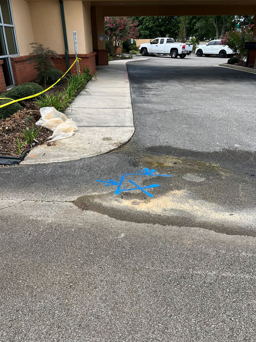 Parking lot with blue markings on asphalt and yellow caution tape near a building entrance.