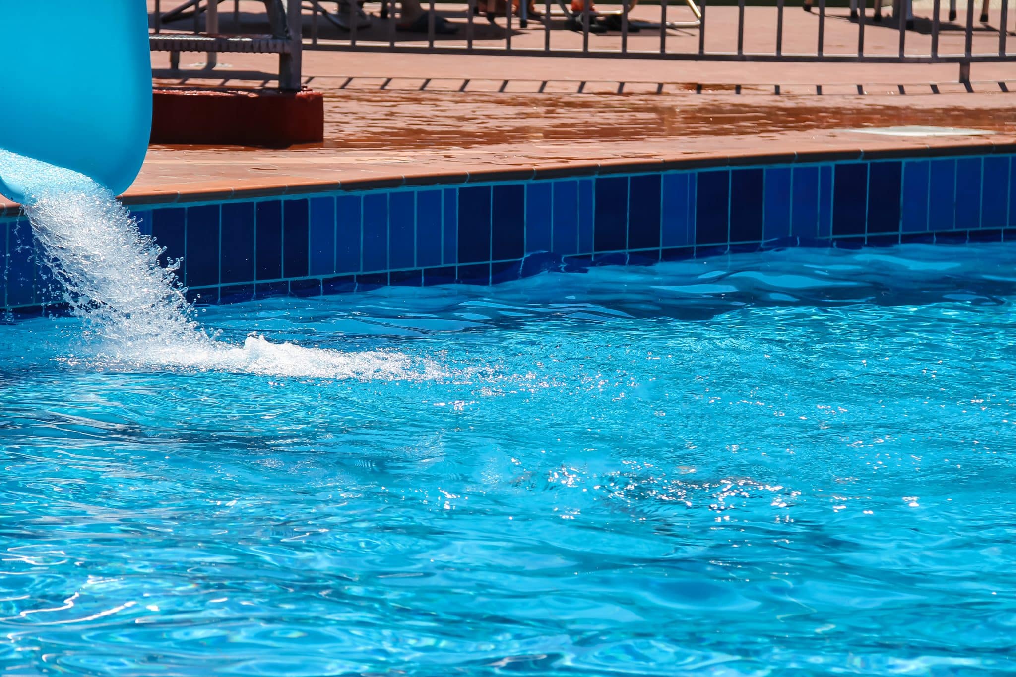Water slide pouring into a bright blue swimming pool.